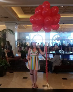 a woman standing in a room with red balloons