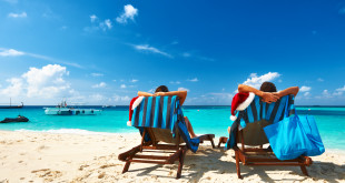 two people sitting in chairs on a beach