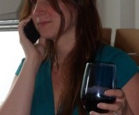 a woman holding a glass of wine and talking on a cell phone