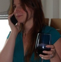 a woman holding a glass of wine and talking on a cell phone