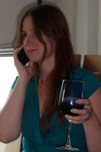 a woman holding a glass of wine and talking on a cell phone