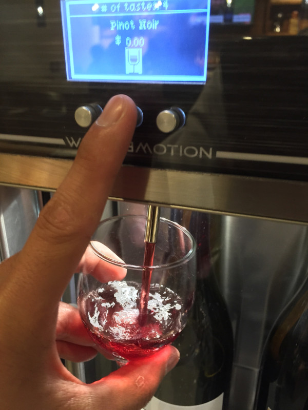 Hold your glass under the spigot and push a button.  Each wine selection seems to have three buttons, and it didn’t seem to make a difference which button was pushed