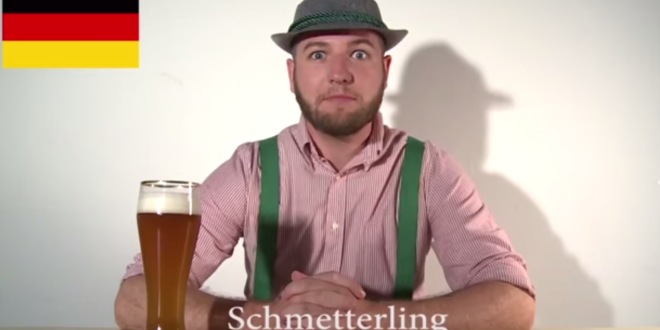 a man in a hat and suspenders sitting at a table with a glass of beer