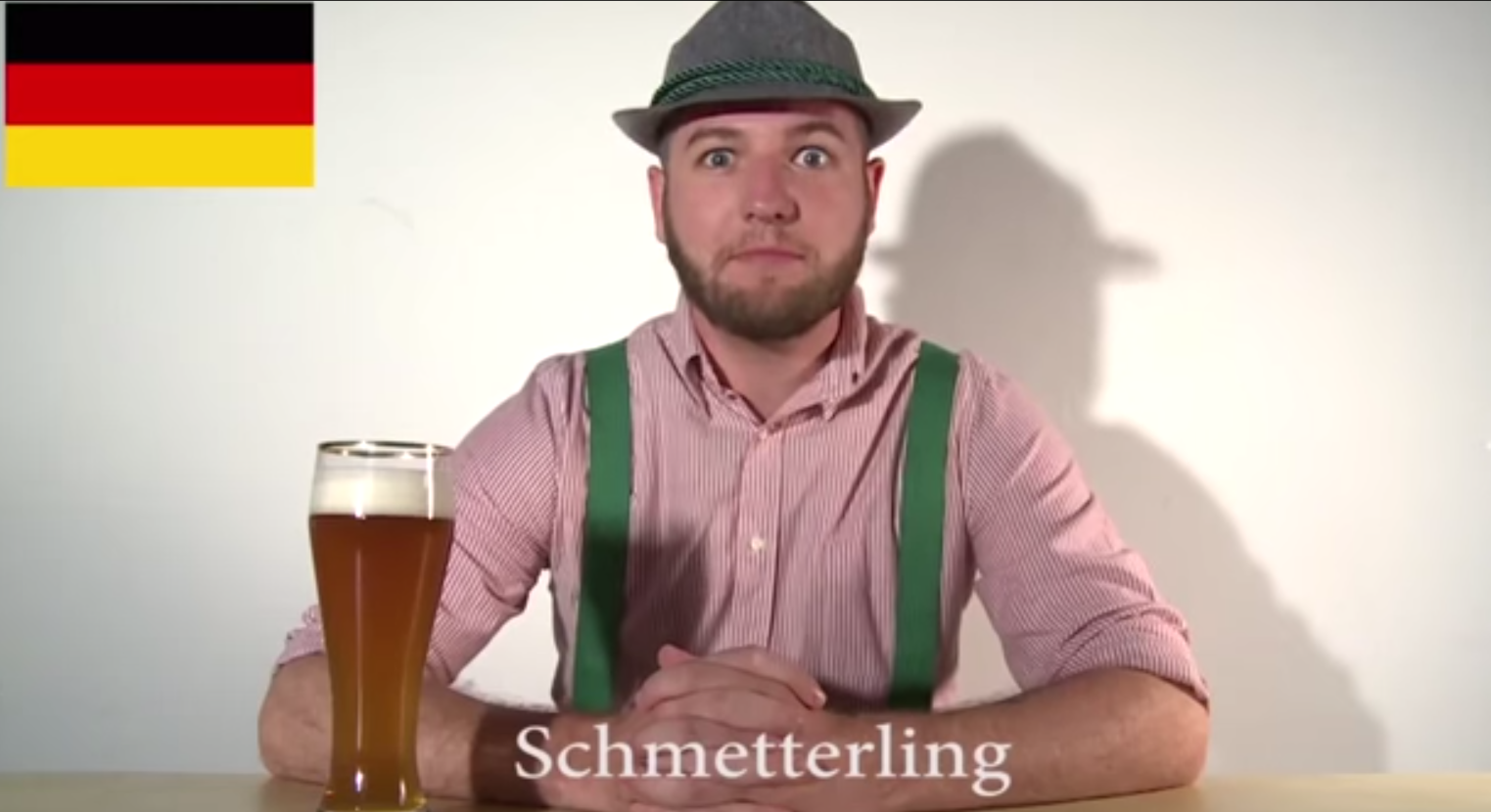 a man in a hat and suspenders sitting at a table with a glass of beer