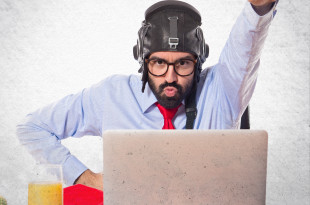 a man in a helmet with his fist up in front of a laptop