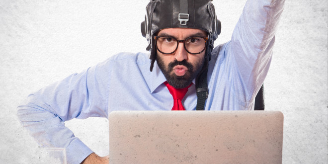 a man in a helmet with his fist up in front of a laptop