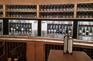 a beverage dispenser with wine glasses on the shelf