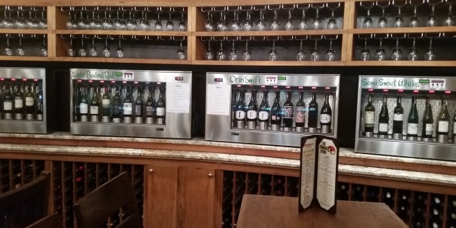 a beverage dispenser with wine glasses on the shelf