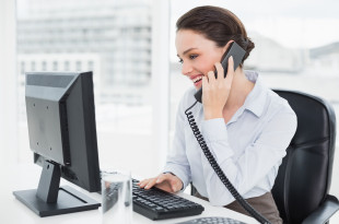 a woman on the phone and looking at a computer