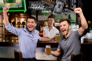 a group of men sitting at a bar holding beer glasses