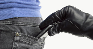 a hand in a glove pulling a cell phone out of a pocket