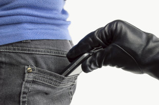 a hand in a glove pulling a cell phone out of a pocket