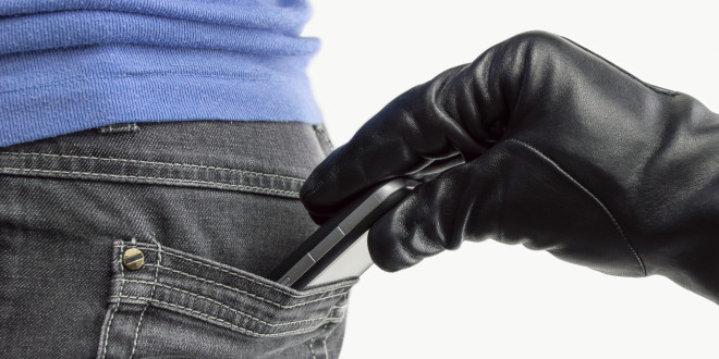 a hand in a glove pulling a cell phone out of a pocket