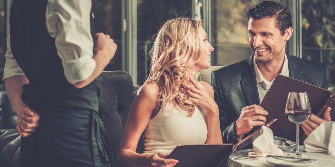 a man and woman sitting at a table with a menu