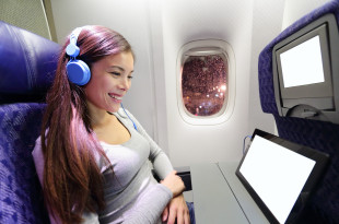 a woman wearing headphones and sitting in an airplane