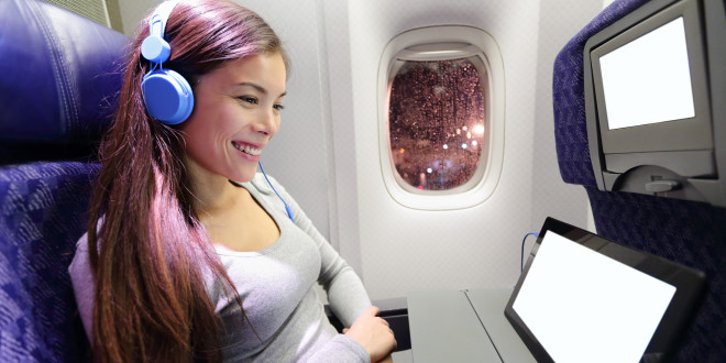 a woman wearing headphones and sitting in an airplane