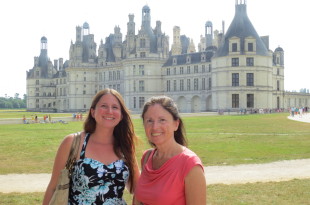 two women standing in front of a large castle