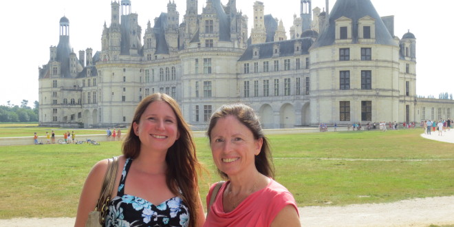 two women standing in front of a large castle