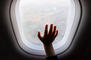a child's hand reaching out of an airplane window