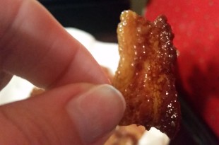 a hand holding a piece of bacon