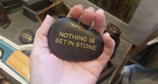 a hand holding a black stone with gold text