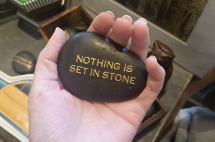 a hand holding a black stone with gold text