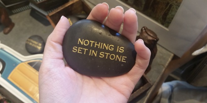 a hand holding a black stone with gold text