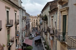 a street between buildings with cars and people