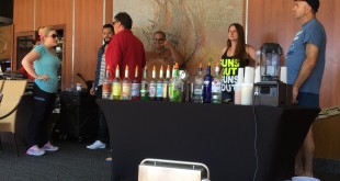 a group of people standing around a table with drinks