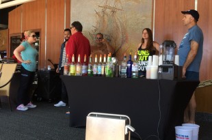 a group of people standing around a table with drinks