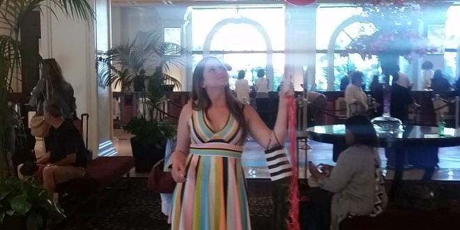 a woman standing in a room with a bunch of red balloons