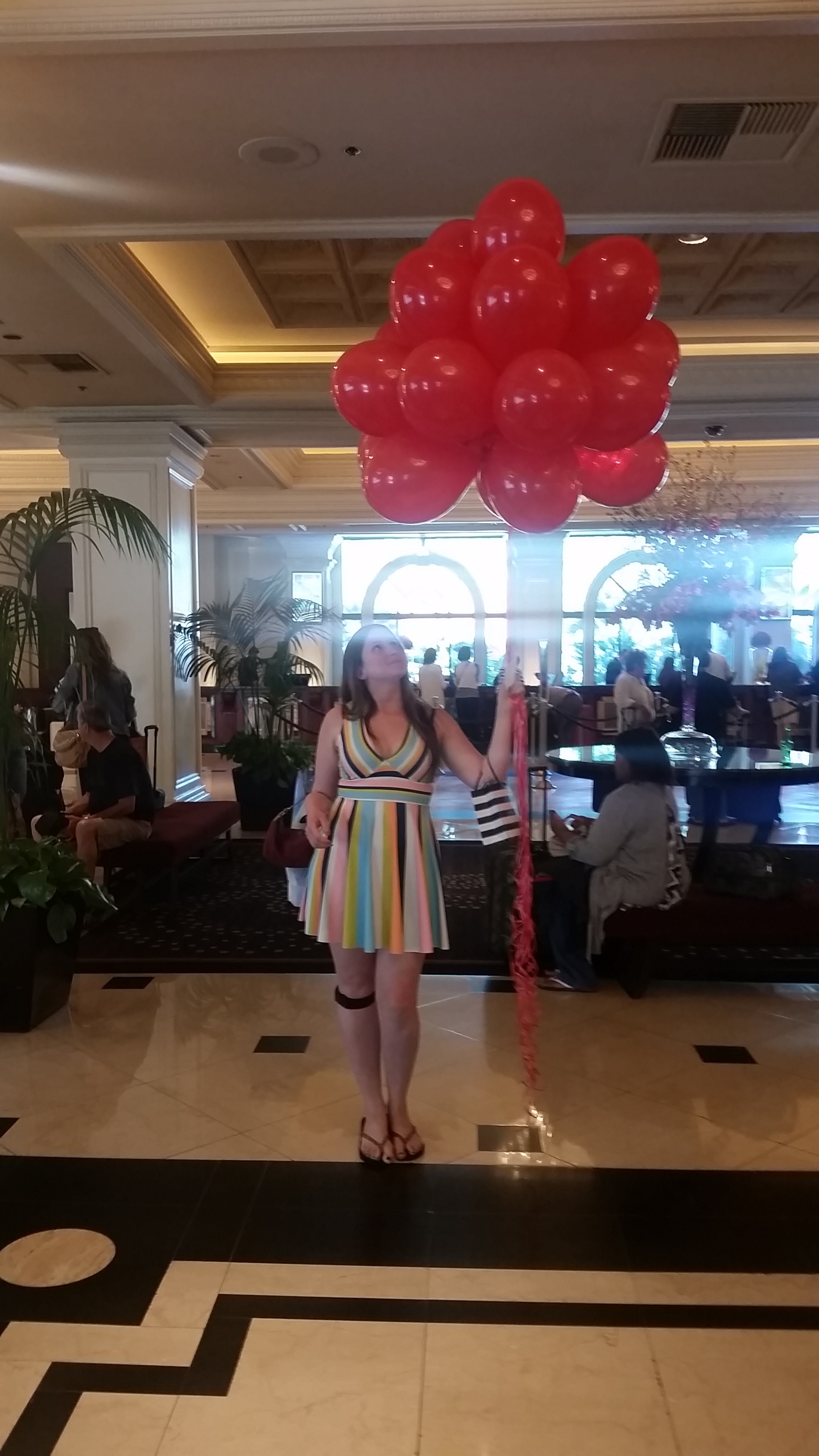 a woman standing in a room with a bunch of red balloons