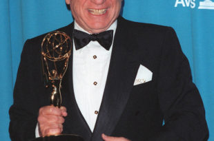 a man in a tuxedo holding a trophy