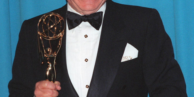 a man in a tuxedo holding a trophy