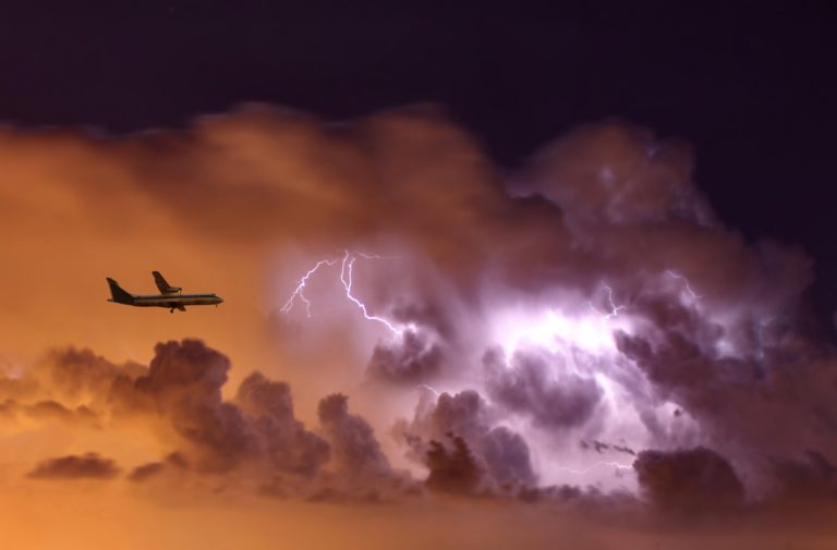 a plane flying in the sky with lightning