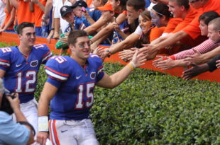 a football player in a blue uniform with a crowd of people clapping