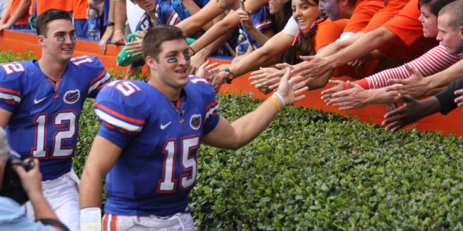 a football player in a blue uniform with a crowd of people clapping