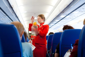 a woman in a red uniform holding a bag in a plane
