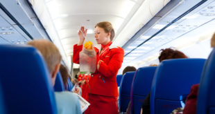 a woman in a red uniform holding a bag in a plane