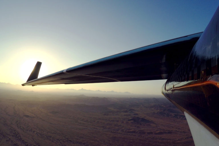 an wing of an airplane over a desert
