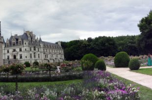 a large white building with a garden and trees with Cawdor Castle in the background