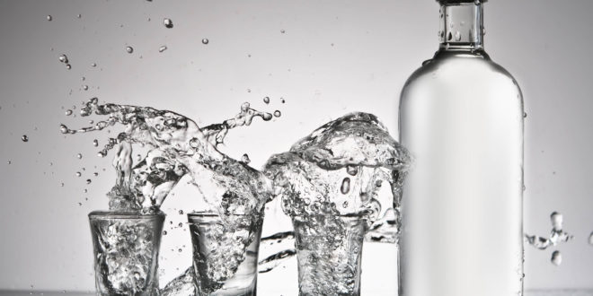 a bottle and shot glasses with water splashing