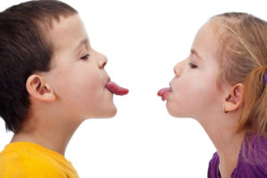 a boy and girl sticking their tongues out