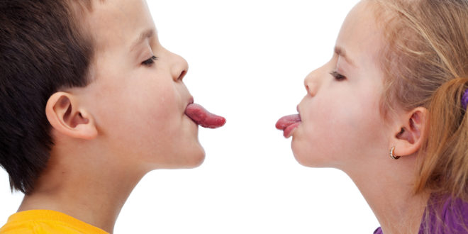 a boy and girl sticking their tongues out