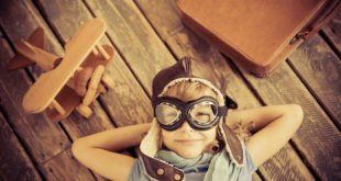a child wearing goggles and a hat lying on a wooden surface