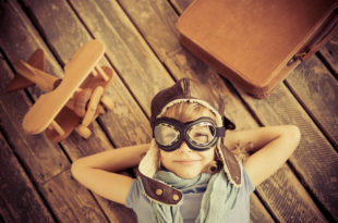 a child wearing goggles and a hat lying on a wooden surface