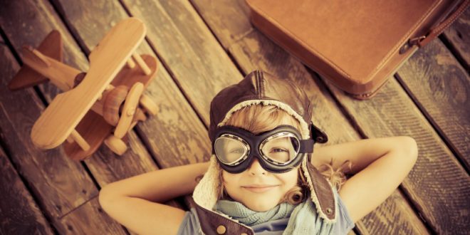 a child wearing goggles and a hat lying on a wooden surface