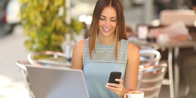 a woman sitting at a table with a laptop and a phone