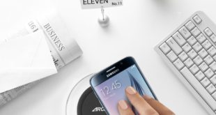 a hand holding a phone on a wireless charger