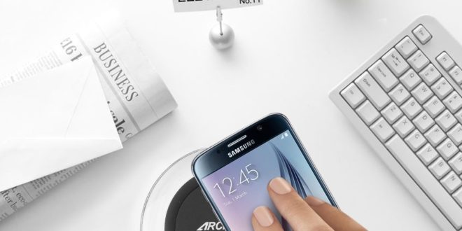 a hand holding a phone on a wireless charger
